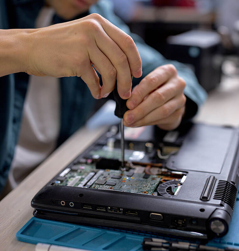 Image of man's hands turning a screwdriver in the underside of an upside down laptop computer